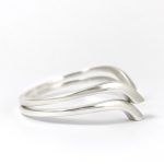 Pulseras de plata con forma geométrica curva y diseño minimalista.