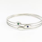 Combinació de dues polseres de plata amb disseny geomètric estilitzat amb maragda verda i safir blau engastats.