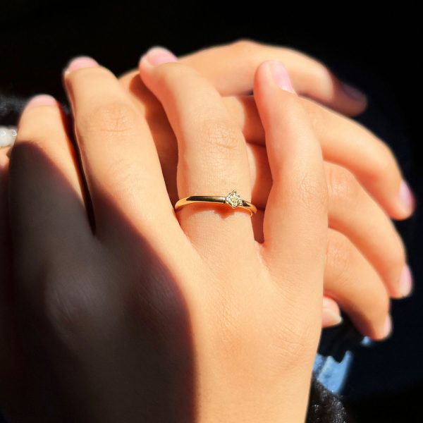 Main féminine portant une fine bague artisanale en or avec détail ancien et pierre centrale claire