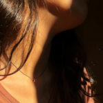 Femme portant un collier en argent oxydé avec pendentif fin en or, feuilles délicates de style ancien