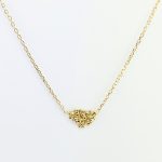 Collar de oro artesanal con colgante de bolitas agrupadas en forma triangular irregular, acabado brillante que capta la luz