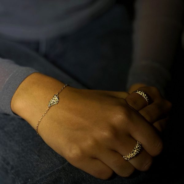 Mujer con pulsera de oro artesanal con detalle de bolitas agrupadas, diseño orgánico y brillante que resplandece al moverse