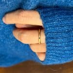 Main féminine avec fine bague en or recyclé faite sur mesure, design minimaliste avec saphir bleu serti en étoile et finition polie artisanale.