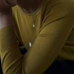 Cadena llarga de plata oxidada amb penjolls tipus amulet i tanca d’or, sobre jersei mostassa