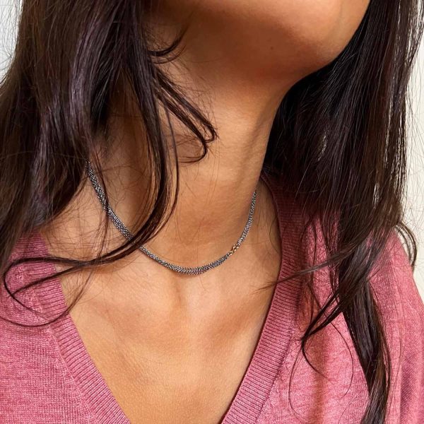 Collaret de quatre cadenetes fines de plata oxidada superposades amb tanca d’or, sobre samarreta rosa amb escot