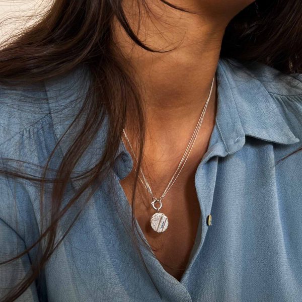 Collier en argent fait main avec pendentif gravé style ancien et quatre saphirs bleus, porté sur une chemise bleue