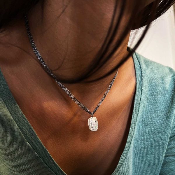 Collier en argent fait main avec pendentif gravé style ancien et tourmaline rose, émeraude verte et saphir bleu, porté sur une chemise verte