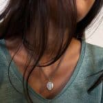 Collier en argent avec pendentif ovale à gravure ancienne, porté sur un t-shirt vert