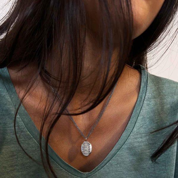 Collier en argent avec pendentif ovale à gravure ancienne, porté sur un t-shirt vert