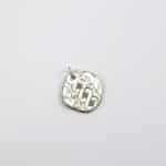 Penjoll rodó de plata amb gravat ondulat d'estil antic i tres maragdes verdes, sobre fons blanc