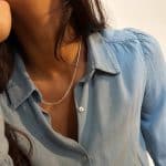 Collaret de plata amb tres cadenetes fines superposades, sobre camisa blava amb coll obert