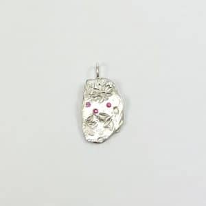 Penjoll artesanal de plata amb gravat antic i tres safirs roses, sobre fons blanc neutre