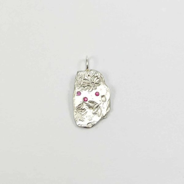 Pendentif en argent fait main avec gravure ancienne et trois saphirs roses, sur fond blanc neutre