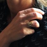 Main avec deux bagues entrelacées, bagues à ondulation organique en argent plaqué or.