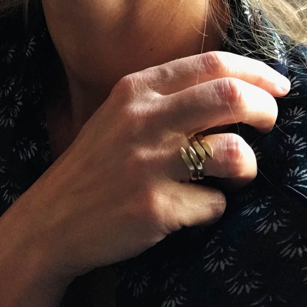 Mà amb dos anells que s'entrelacen, anells amb ondulación orgánica de plata xapats or