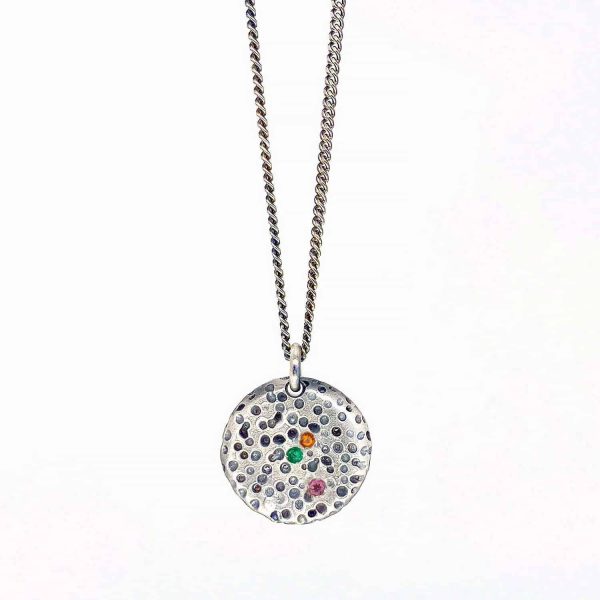 Collier en argent oxydé avec médaille ronde inspirée d’une pierre érodée sertie d’émeraude citrine et tourmaline rose.
