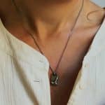 Dona amb collaret artesanal de plata oxidada amb medalla rectangular amb relleu inspirat en paisatge natural.