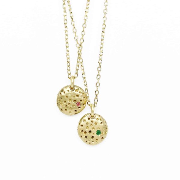 Colliers artisanaux en argent plaqué or avec médailles à texture rugueuse inspirée de pierre érodée serties de tourmaline rose et d’émeraude verte conçus pour être portés en superposition.