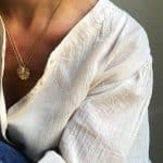 Collarets amb medalles ovalades de plata xapada en or amb relleu d’onada marina portats superposats per model.