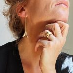 Femme portant une boucle d’oreille longue en argent plaqué or au design stylisé et élégant.