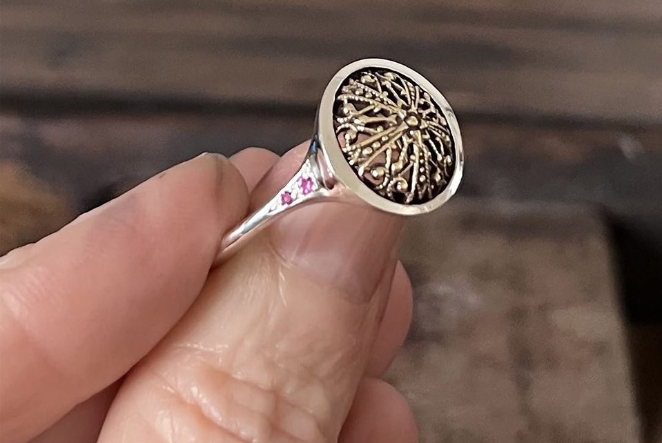 Anillo de plata de joyería artesanal con detalle antiguo engastado y dos zafiros rosas a cada lado.