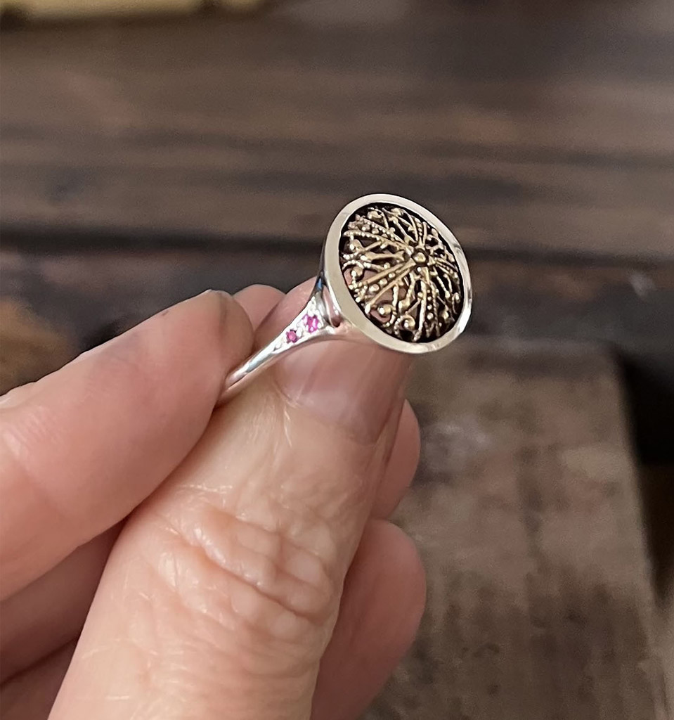 Anillo de plata de joyería artesanal con detalle antiguo engastado y dos zafiros rosas a cada lado.